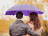 A couple standing happily together and holding a purple umbrella.