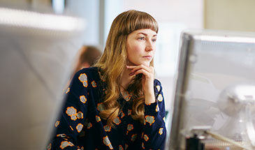 Woman sitting in from of a computer looking thoughtful
