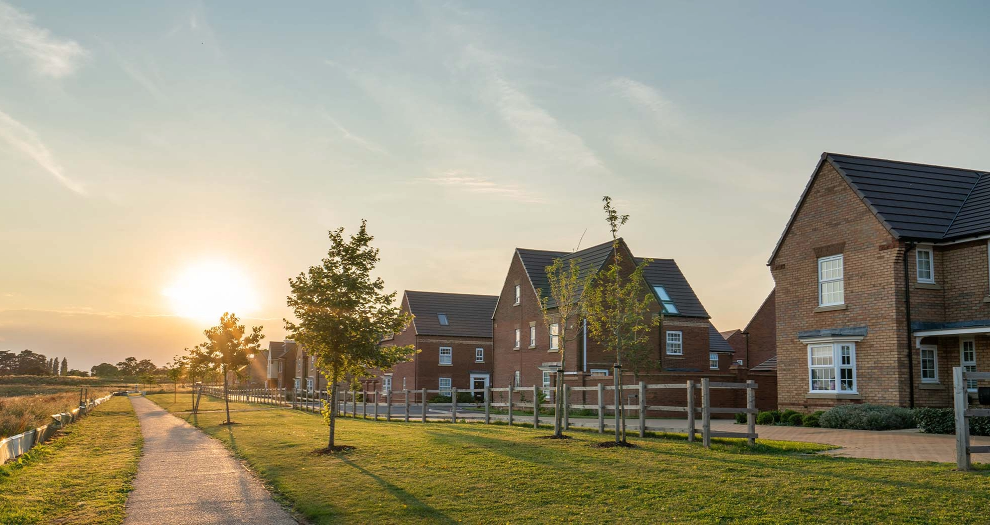 A row of newly built homes with the sun setting in the background