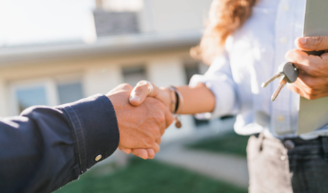 Man shaking hands with a woman holding a set of house keys