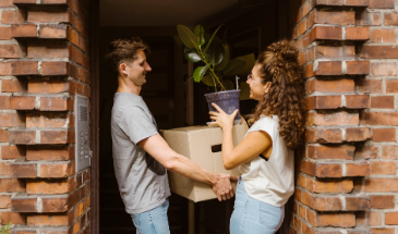 A young couple standing in the front doorway of their new home
