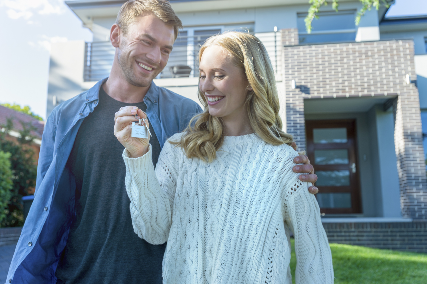 Happy couple smiling and holding the keys to their new home.