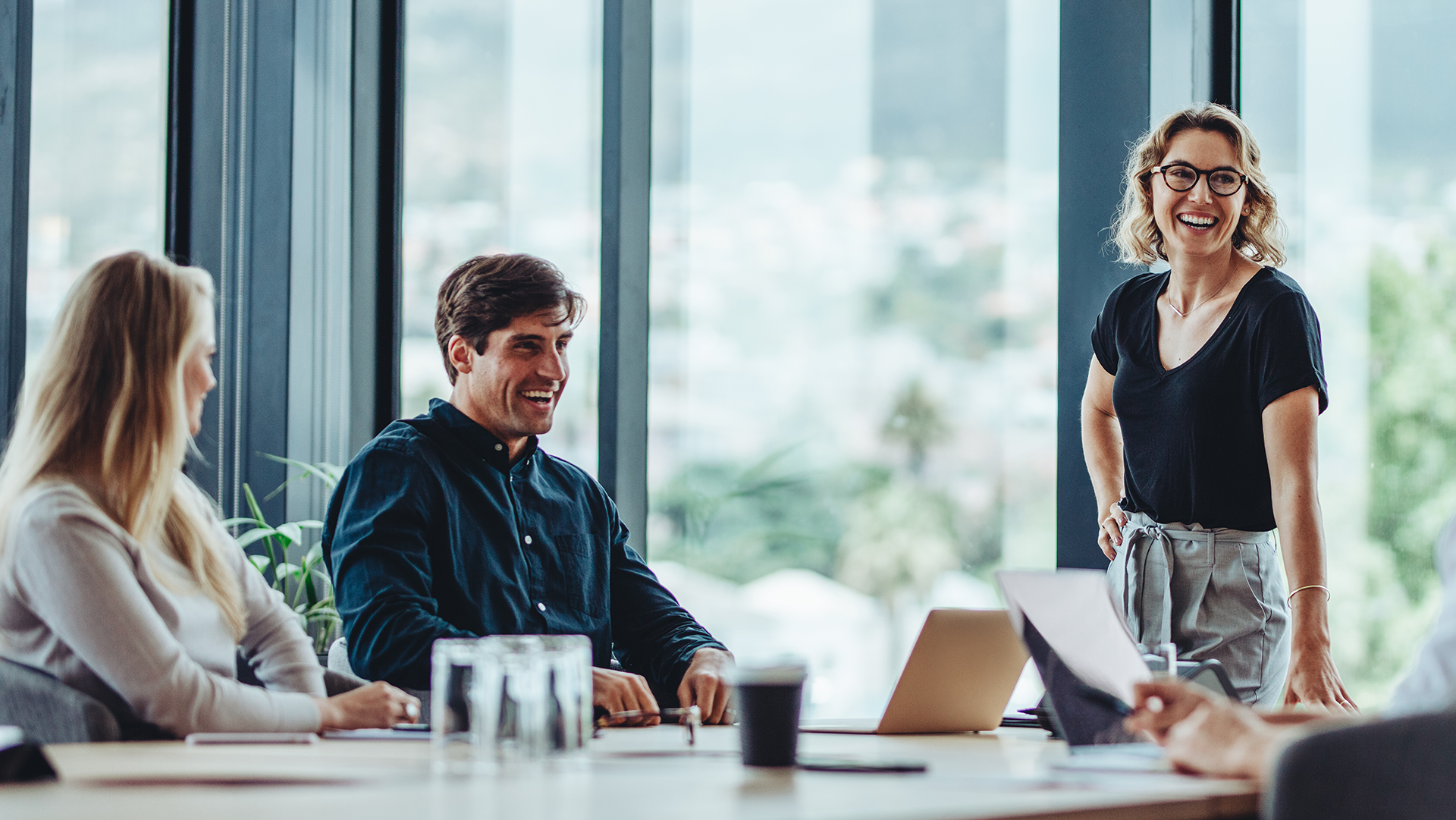 Three colleagues in a meeting room discussing business areas.
