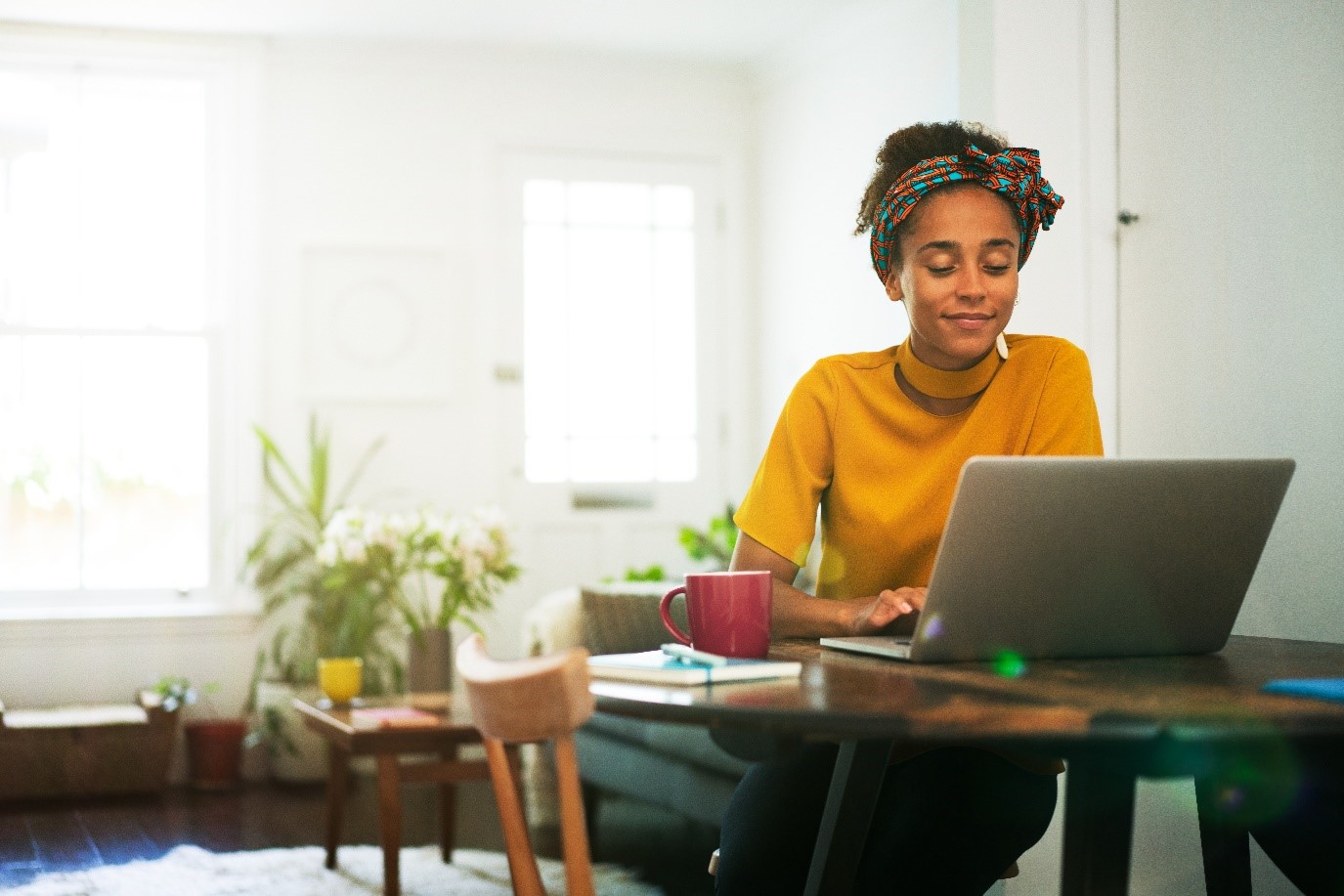 A woman smiling and looking at her laptop screen