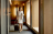 Woman wheeling suitcase along empty hotel corridor