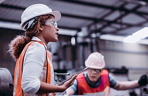 Woman wearing hi vis jacket and hard hat with building site in the background