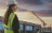 Woman wearing hi vis jacket and hard hat with building site in the background