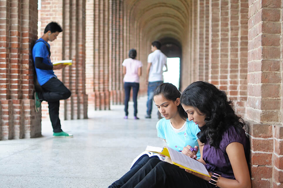 Students in an outdoor archway reading books and exploring.