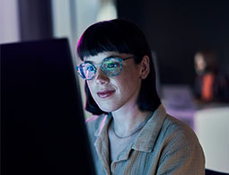 Woman sitting at a computer with the screen reflected in her glasses