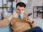 Man sitting on a sofa drinking from a mug looking at his phone